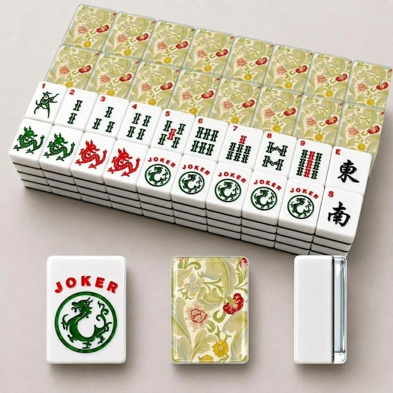 May include: A set of white Mahjong tiles featuring green and red ink designs, including dragons, numbers, and Joker labels. The back of each tile displays a detailed floral pattern in shades of yellow, green, and red on a light cream background.