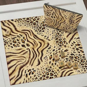 May include: A square mat and a matching zippered pouch featuring a tan, brown, and black animal print pattern. Five small rectangular mahjong tiles with green and black Chinese characters are scattered across the surface of the mat.