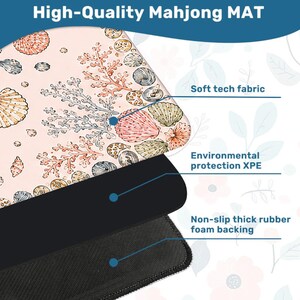 May include: A Mahjong mat featuring a light pink surface with a pattern of various seashells and coral. The mat is composed of three layers: a soft tech fabric top, an environmental protection XPE middle layer, and a non-slip thick rubber foam backing.