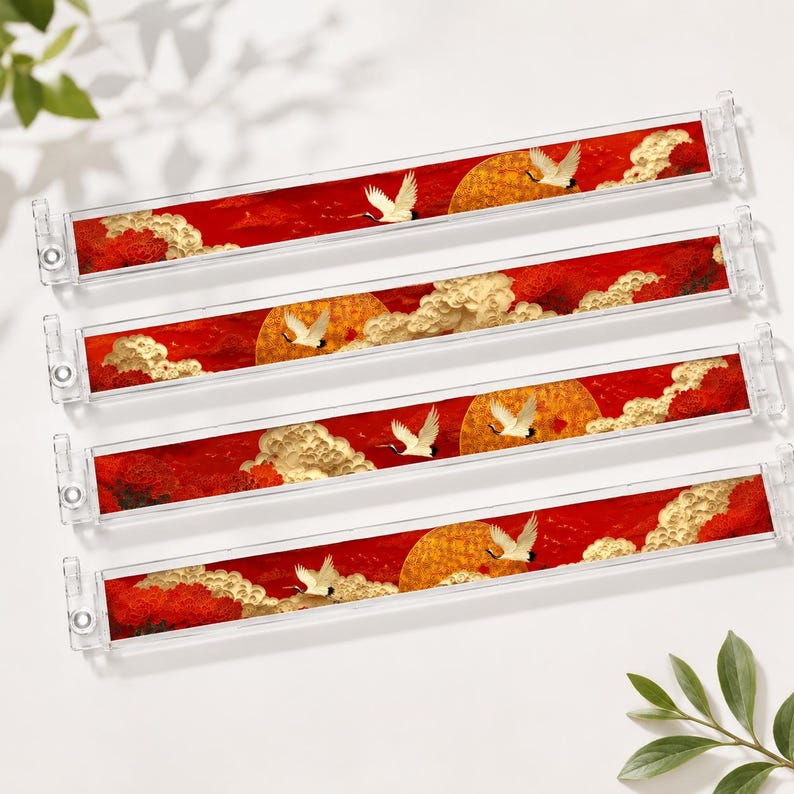 May include: Four clear acrylic drawer pulls with a red, gold, and white design. The design features a red background with a golden sun, white clouds, and white cranes in flight. The pulls have a rectangular shape.