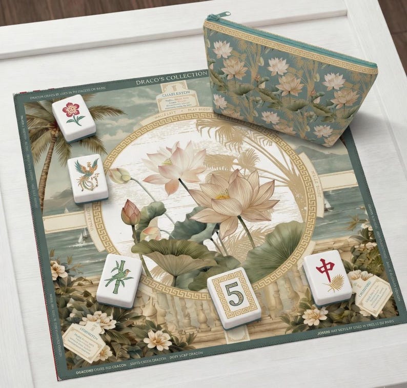 Puede incluir: Un juego de mahjong decorativo con fichas con dise&ntilde;os florales y simb&oacute;licos, colocado sobre un tapete a juego con un motivo de flor de loto. Tambi&eacute;n se incluye una bolsa con cremallera a juego con un estampado de loto.