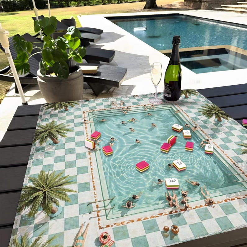 May include: A decorative table mat featuring a pool scene with swimmers, palm trees, and a checkered pattern. The mat is adorned with colorful game pieces. A bottle of champagne and a glass are on the table, suggesting a leisure activity.