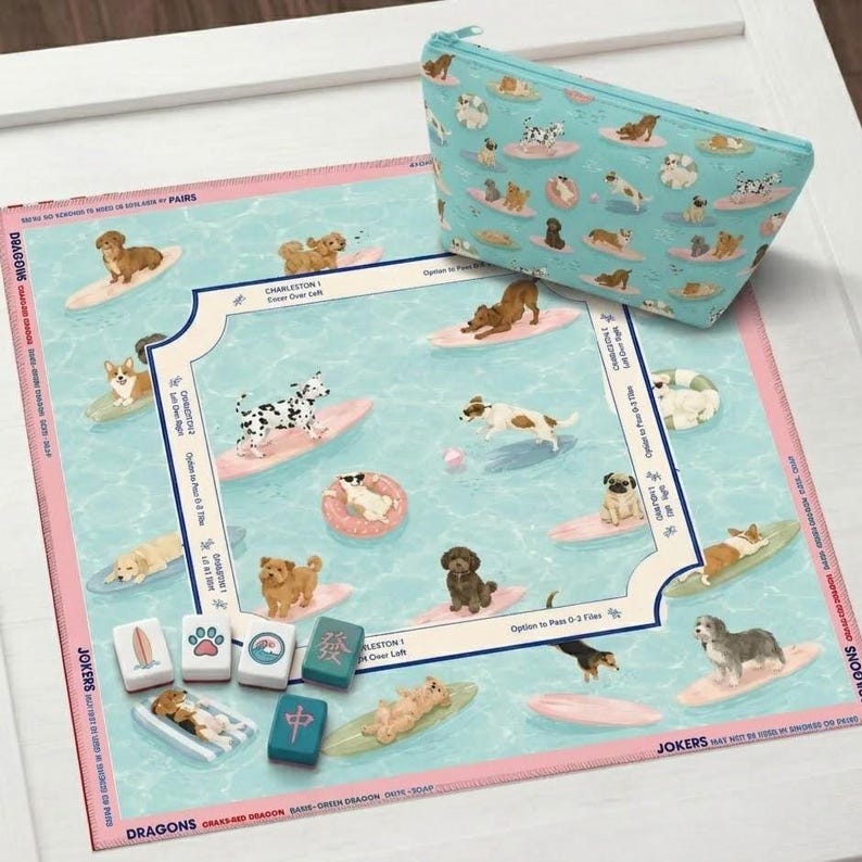 May include: A dog-themed game set featuring a board with dogs surfing on waves, a matching zippered pouch, and game tiles. The board has a light blue background with pink borders and the text "DRAGONS" and "JOKERS".
