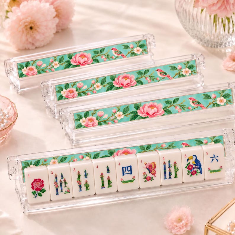 May include: Four clear acrylic mahjong tile racks featuring a decorative insert with a teal background, pink peony flowers, and small birds. The front rack holds nine white mahjong tiles with colorful floral, bird, butterfly, and numeric designs.