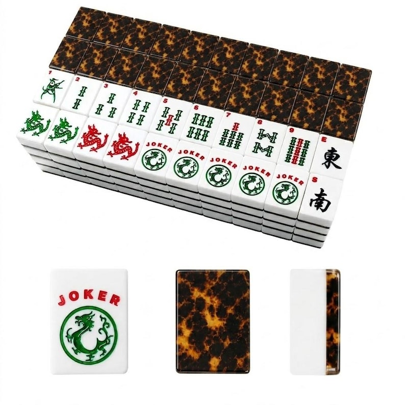 May include: A set of Mahjong tiles featuring a white face with green and red ink designs, including numbers, dragons, and Joker text. The reverse side of each tile displays a brown and black tortoiseshell pattern. Three individual tiles are shown.
