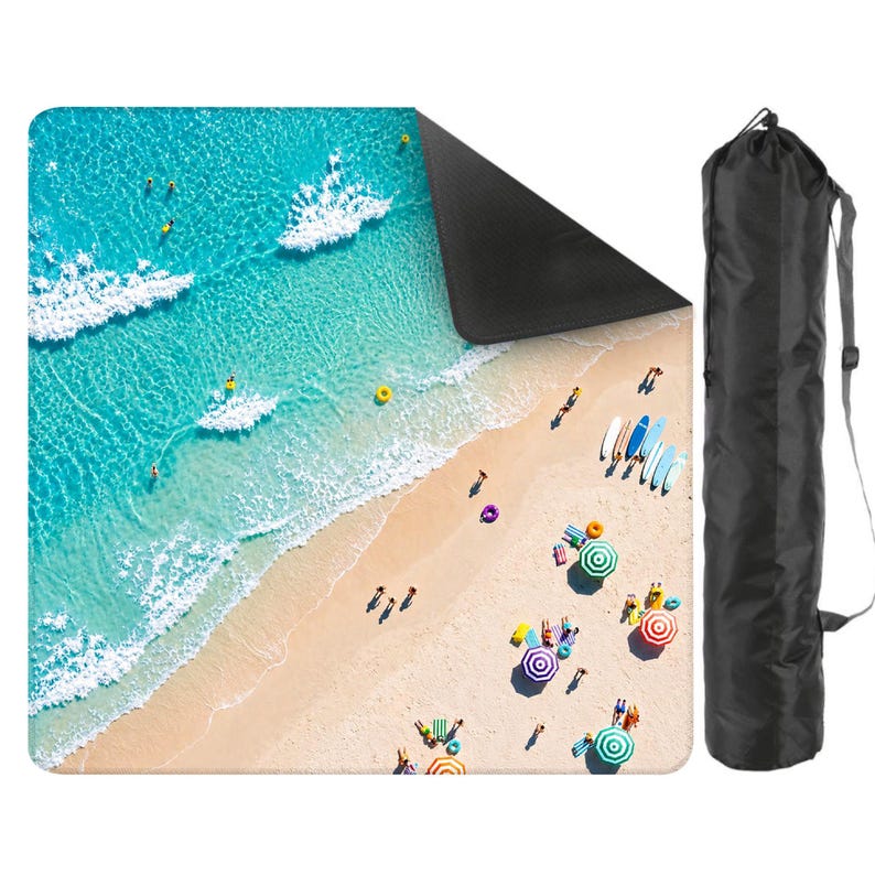 May include: A square outdoor mat featuring an aerial view of a sandy beach with turquoise ocean waves, colorful umbrellas, and people. The mat has a solid black underside and is accompanied by a black cylindrical carrying bag with a shoulder strap.
