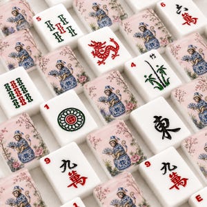 Op de afbeelding: Een verzameling witte Mahjong-tegels met verschillende ontwerpen. Sommige tegels tonen rode Chinese karakters, terwijl andere illustraties van apen, draken en bamboe tonen. De tegels zijn in een raster gerangschikt.