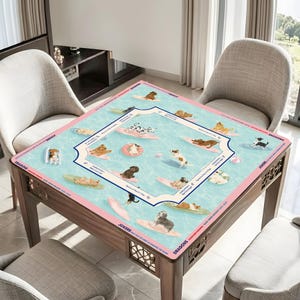 May include: A square table with a decorative mat featuring dogs surfing on surfboards in a pool. The mat has a light blue background with pink borders and a decorative frame. The table is made of wood.