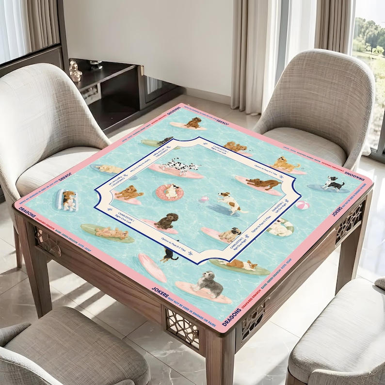 May include: A square table with a decorative mat featuring dogs surfing on surfboards in a pool. The mat has a light blue background with pink borders and a decorative frame. The table is made of wood.