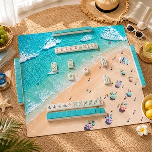 May include: A square mahjong mat featuring a printed beach scene with turquoise ocean waves and sandy shore. The mat includes scattered mahjong tiles with Chinese characters and symbols, alongside miniature beach umbrellas and figures.