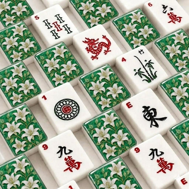 Pu&ograve; includere: Una collezione di tessere rettangolari da mahjong disposte in una griglia. Alcune tessere presentano gigli bianchi su sfondo verde, mentre altre mostrano caratteri cinesi neri e rossi, un drago rosso, un gambo di bamb&ugrave; e un emblema circolare.