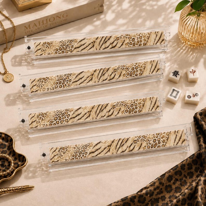 May include: Four clear acrylic mahjong tile racks featuring a central horizontal strip with a tan and brown animal print pattern consisting of leopard spots and tiger stripes. The racks are rectangular with small black end caps on each side.