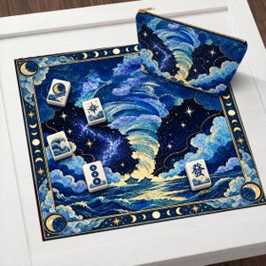 Può includere: Un tappetino da mahjong quadrato e una pochette con cerniera abbinata raffiguranti un cielo notturno blu scuro con un tornado dorato, nuvole, stelle e fasi lunari. Quattro tessere bianche da mahjong con illustrazioni blu e oro sono posate.