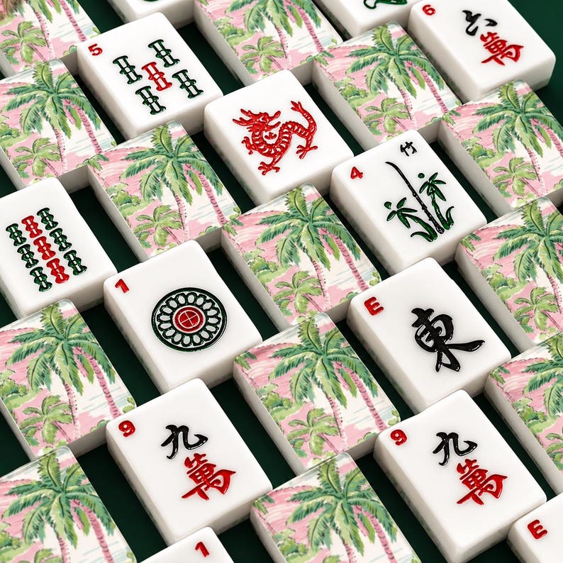 May include: A collection of white Mahjong tiles with red, green, and black symbols and numbers. Some tiles feature a pink and green palm tree design. The tiles are arranged on a dark green surface.