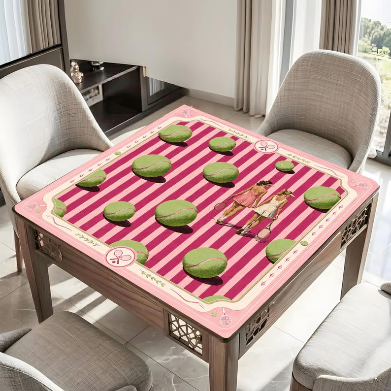 Puede incluir: Un mantel cuadrado con un patr&oacute;n de rayas rosas y rosa oscuro, gr&aacute;ficos de pelotas de tenis verdes e ilustraciones de dos tenistas. El borde incluye peque&ntilde;os iconos de raquetas de tenis y l&iacute;neas decorativas sobre un fondo rosa claro.