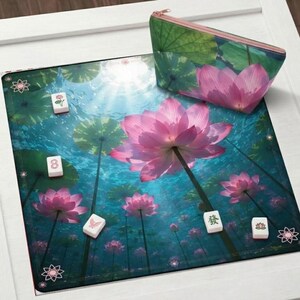 May include: A decorative Mahjong set featuring a vibrant pink lotus flower design. The set includes a matching zippered pouch and tiles. The background depicts an underwater scene with lotus flowers and lily pads. The set is on a white surface.