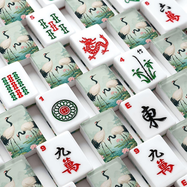 Może przedstawiać: Zbi&oacute;r białych płytek do gry w Mahjong z r&oacute;żnymi symbolami i ilustracjami. Niekt&oacute;re płytki przedstawiają czerwone smoki, zielony bambus i obrazy żurawi. Inne płytki wyświetlają chińskie znaki i liczby w kolorze czerwonym i czarnym.