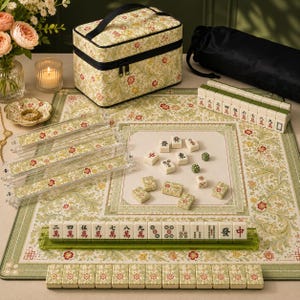 May include: A Mahjong set featuring cream-colored tiles with red, green, and black characters, a floral patterned play mat, four clear acrylic tile racks, a matching floral storage case, two green dice, and a black drawstring bag for storage.