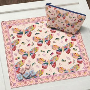 May include: A square fabric mat and a matching zippered pouch, both featuring a light pink background with a repeating pattern of colorful butterflies in shades of yellow, orange, blue, and red. Six small rectangular wooden tiles are included.