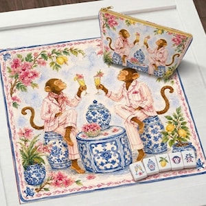 Op de afbeelding: Een decoratieve set met een grillige illustratie van apen in roze pyjama's die toosten op drankjes. De set bevat een vierkante mat, een etui met ritssluiting en mahjongtegels. Het ontwerp bevat blauw-witte porseleinstijl elementen en bloemaccenten.