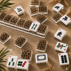 Puede incluir: Una colecci&oacute;n de fichas de Mahjong blancas y con estampado de leopardo dispuestas sobre una superficie marr&oacute;n claro. Algunas fichas presentan caracteres chinos y dise&ntilde;os florales. Las piezas del juego son una mezcla de formas rectangulares y cuadradas.
