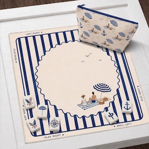 May include: A beach-themed Mahjong set with a matching cosmetic bag. The set includes a cream-colored mat with blue stripes and a beach scene. The bag and mat feature illustrations of beach umbrellas, anchors, and people.