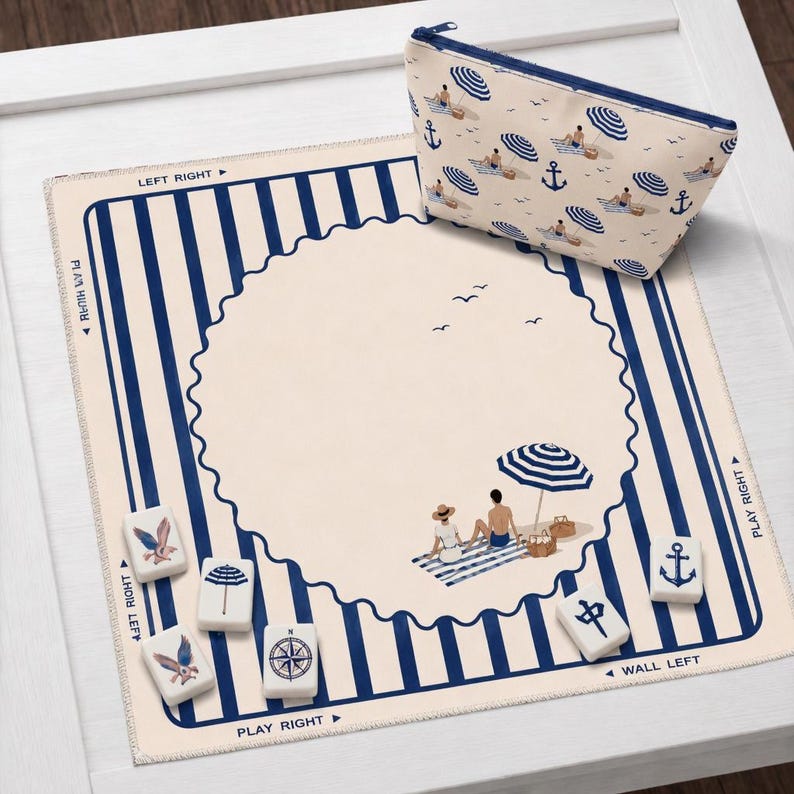 May include: A beach-themed Mahjong set with a matching cosmetic bag. The set includes a cream-colored mat with blue stripes and a beach scene. The bag and mat feature illustrations of beach umbrellas, anchors, and people.