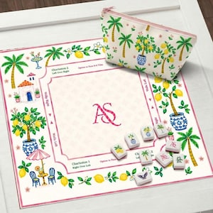 May include: A decorative game set featuring a cream-colored game board with a pink border, palm trees, and lemon tree illustrations. Includes a matching zippered pouch and game tiles. The board has the initials "AS" in the center.