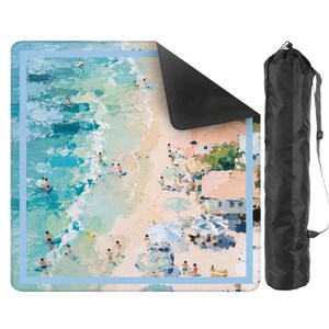 May include: A rectangular yoga mat with a beach scene design and a light blue border. The artwork shows people on a beach with water and buildings. Includes a black carry bag with a shoulder strap.