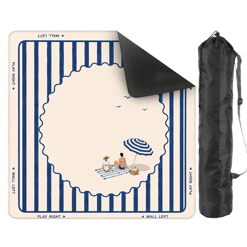 May include: A square beach mat with a blue and white striped border and a central cream-colored design featuring a beach scene with an umbrella and two figures. Includes a black carrying bag.