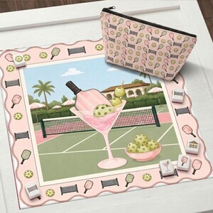 May include: A pink and green pickleball-themed decorative mat with a matching cosmetic bag. The mat features a martini glass with a pickleball and a pickleball court scene. The cosmetic bag has a repeating pattern of pickleball paddles and balls.