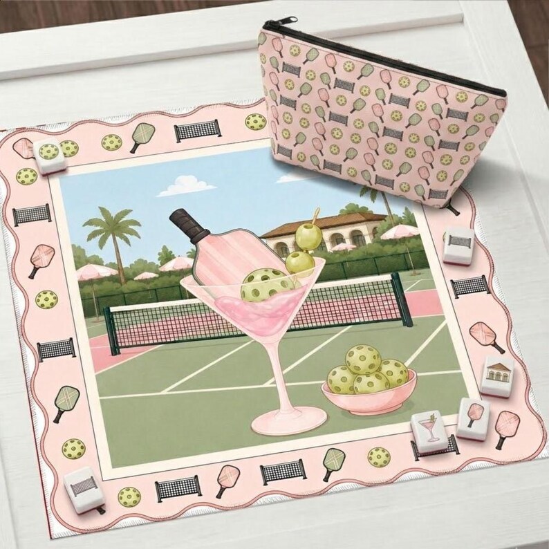 May include: A pink and green pickleball-themed decorative mat with a matching cosmetic bag. The mat features a martini glass with a pickleball and a pickleball court scene. The cosmetic bag has a repeating pattern of pickleball paddles and balls.