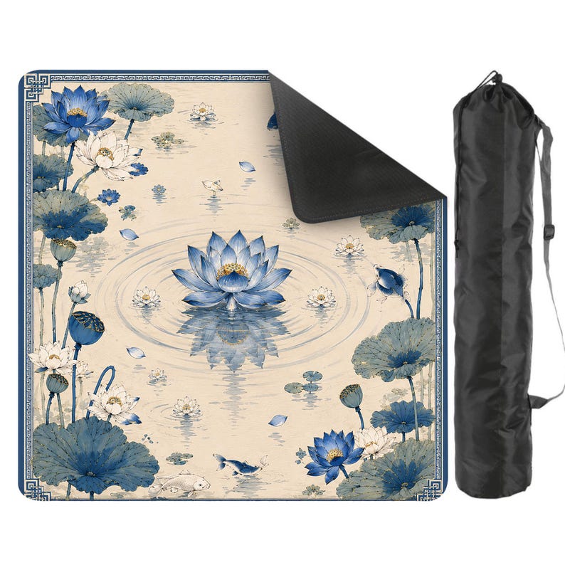 May include: A square mat featuring a blue and cream lotus flower and koi fish pattern with a geometric border, shown with one corner folded to reveal a black underside, accompanied by a black cylindrical carrying bag with a shoulder strap.