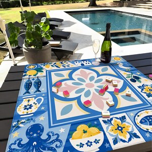 May include: A colorful, patterned game board with a floral design in the center, surrounded by blue, white, and yellow geometric shapes. Small game pieces are scattered across the board. A bottle of wine and a glass are on the table.