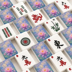Op de afbeelding: Een verzameling rechthoekige mahjongtegels gerangschikt in een raster. Sommige tegels tonen geschilderde roze lotusbloemen op blauw water, terwijl andere zwarte en rode Chinese karakters, een rode draak, een groene bamboestengel en een cirkelvormig patroon bevatten.