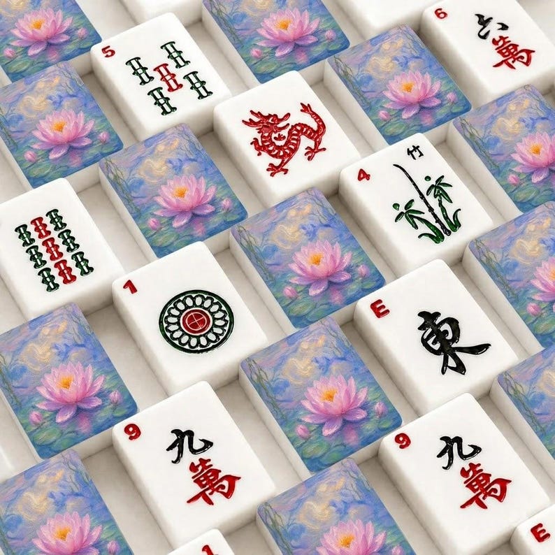 Op de afbeelding: Een verzameling rechthoekige mahjongtegels gerangschikt in een raster. Sommige tegels tonen geschilderde roze lotusbloemen op blauw water, terwijl andere zwarte en rode Chinese karakters, een rode draak, een groene bamboestengel en een cirkelvormig patroon bevatten.