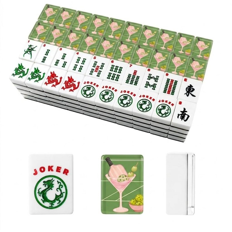 May include: A complete Mahjong set with white tiles featuring green and red symbols, numbers, and characters. The set includes tiles with cocktail and joker designs. The tiles are stacked, with a few individual tiles displayed.
