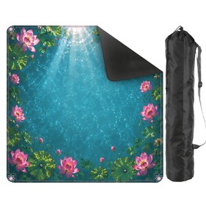 May include: A yoga mat featuring a serene design of pink lotus flowers and lily pads floating on a turquoise water background. The mat has a black underside and comes with a black carrying bag with a shoulder strap. The mat's design evokes a sense of tranquility.