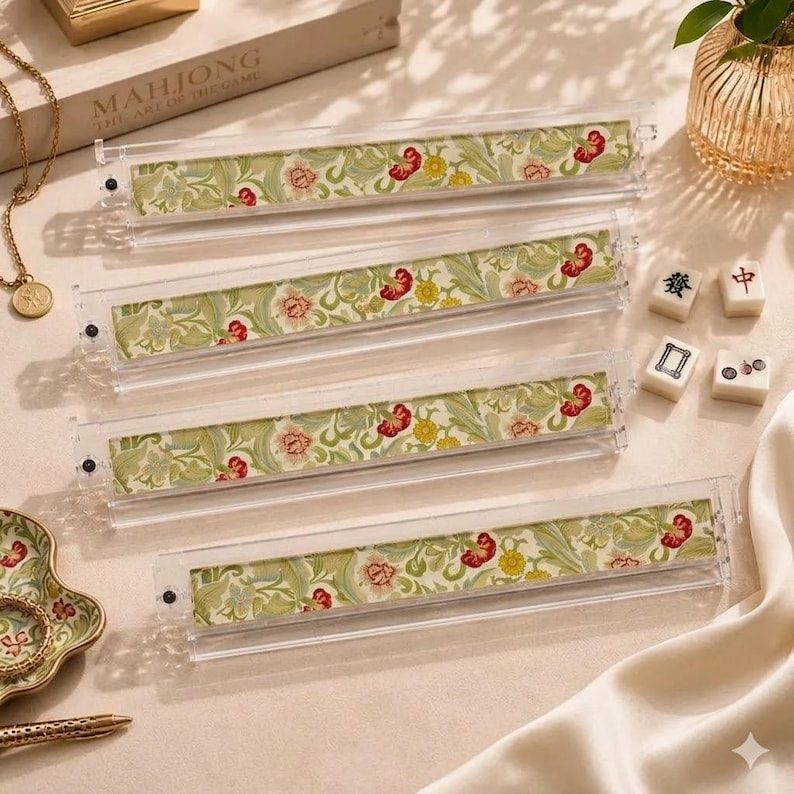 May include: Four clear acrylic mahjong tile racks featuring a decorative insert with a light green background and a repeating floral pattern in shades of red, yellow, and cream. The racks are rectangular with small black end caps on each side.