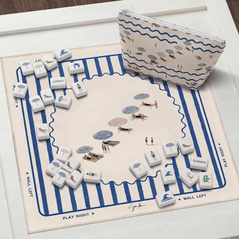 May include: A beach-themed game set with a matching zippered pouch. The game board features a beach scene with umbrellas and people. The game pieces have beach-related icons. The pouch and board have blue and white stripes.