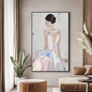 Puede incluir: Pintura abstracta de una mujer con un vestido, vista desde atr&aacute;s. El vestido es blanco con acentos iridiscentes azules, rosas y morados. La mujer tiene el pelo oscuro y est&aacute; sentada. La obra est&aacute; enmarcada en un marco rectangular negro.