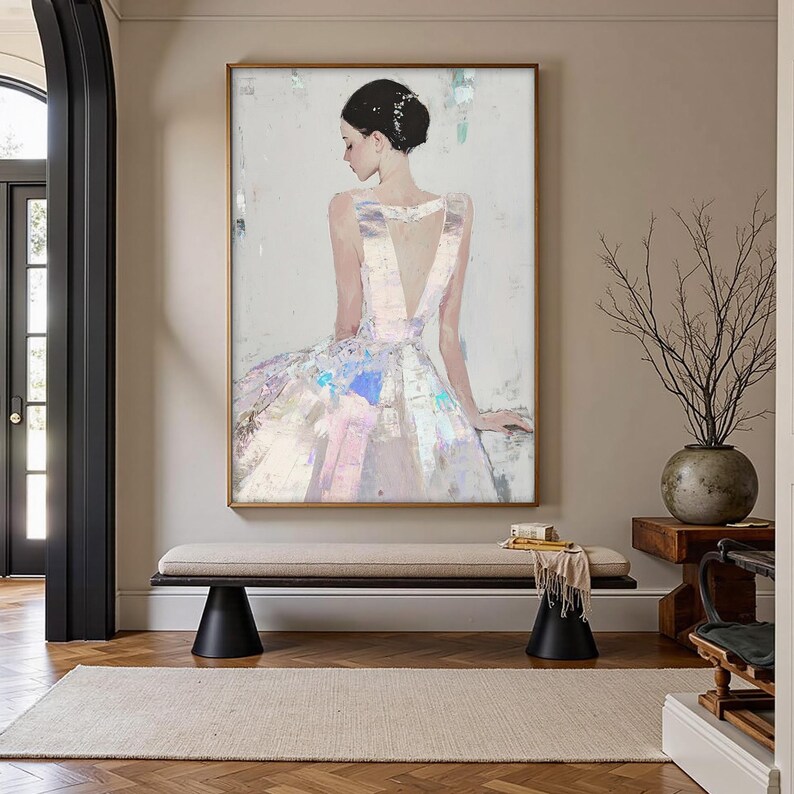 Puede incluir: Pintura abstracta de una mujer con un vestido blanco con la espalda baja. La obra de arte tiene un marco dorado y se exhibe en una habitaci&oacute;n luminosa. El vestido tiene acentos iridiscentes rosas, azules y morados.