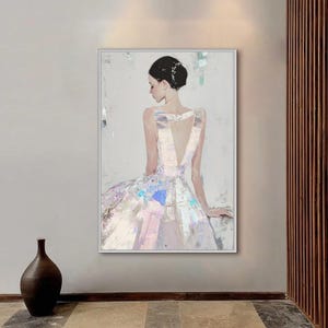 Puede incluir: Pintura al &oacute;leo de una mujer con un vestido blanco con espalda en V profunda. El vestido tiene acentos iridiscentes de rosa, azul y morado. El cabello de la mujer est&aacute; peinado en un mo&ntilde;o. La obra est&aacute; enmarcada en un marco blanco.