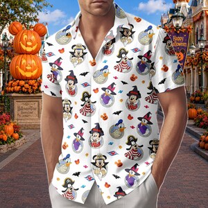 May include: A white short-sleeved button-down shirt featuring an all-over print of Disney characters in Halloween costumes, including Mickey Mouse, Minnie Mouse, Donald Duck, and Goofy, interspersed with small black bats, orange pumpkins, and candies.