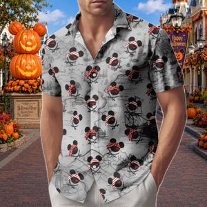 May include: A short-sleeved button-down shirt featuring a light gray background with a repeating pattern of black Mickey Mouse silhouettes wearing red and white striped pirate bandanas over crossed swords, with a subtle map print design.