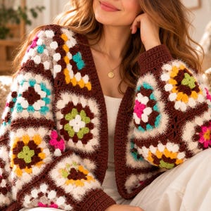 May include: A long-sleeved crochet cardigan featuring a multi-coloured granny square pattern. The garment is constructed with dark brown yarn borders and squares containing white, yellow, bright pink, turquoise, and light green yarn accents.