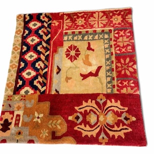 May include: A square, patterned rug with a patchwork design. The rug features a variety of colors, including red, beige, navy, and gold. The design includes geometric shapes and floral motifs, creating a vibrant and textured appearance.