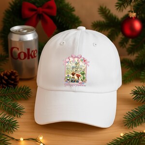 May include: White baseball cap featuring a colorful graphic of a castle and cartoon characters. The cap has a curved brim and a top button. The text "You've got a Friend in me" is printed below the graphic. The cap is set against a festive background.