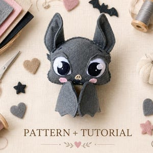 May include: A handmade gray felt bat with large eyes and a cute expression. The bat is surrounded by sewing supplies, including spools of thread, scissors, felt shapes, and a pin cushion. The text "PATTERN + TUTORIAL" is at the bottom.
