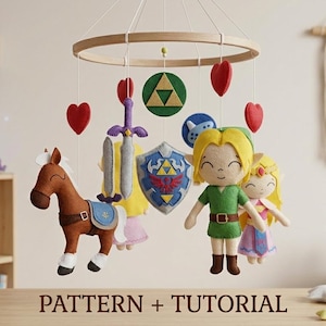Puede incluir: Móvil para bebé hecho a mano con personajes de fieltro de un videojuego. El móvil incluye un caballo marrón, una espada, un escudo y figuras de un niño y una niña. El móvil está suspendido de un aro de madera e incluye acentos de corazón rojo. El texto "PATTERN + TUTORIAL" está en la parte inferior.